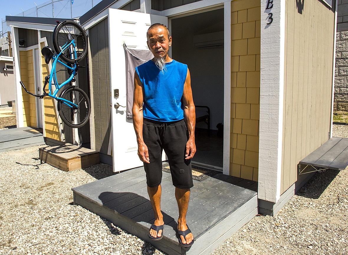 Hoang Nguyen stands in front of his “tiny home” at a San Jose site that gives unhoused people a room of their own 