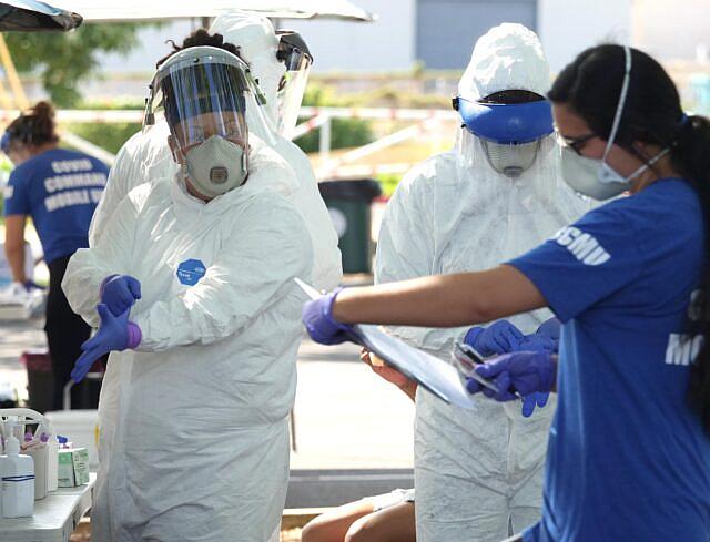 Members of Hawaii’s COVID-19 Command Mobile Unit prepare to collect samples from Oahu residents during a drive-thru event in Kak