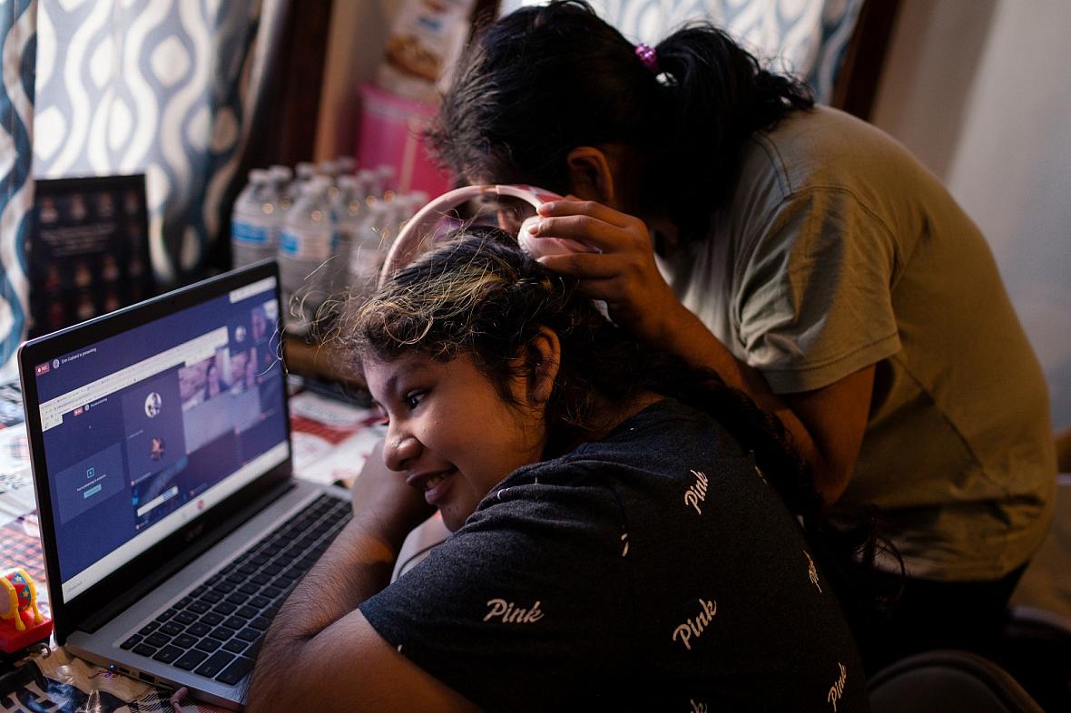 Sarai Camarillo (right) shares headphones with her sister, Isamari Lucero, 13, as she learns remotely from their Little Village 