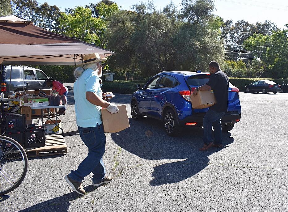 Volunteers help load boxes of food into vehicles after asking drivers how many boxes of food they want on June 4, 2021.