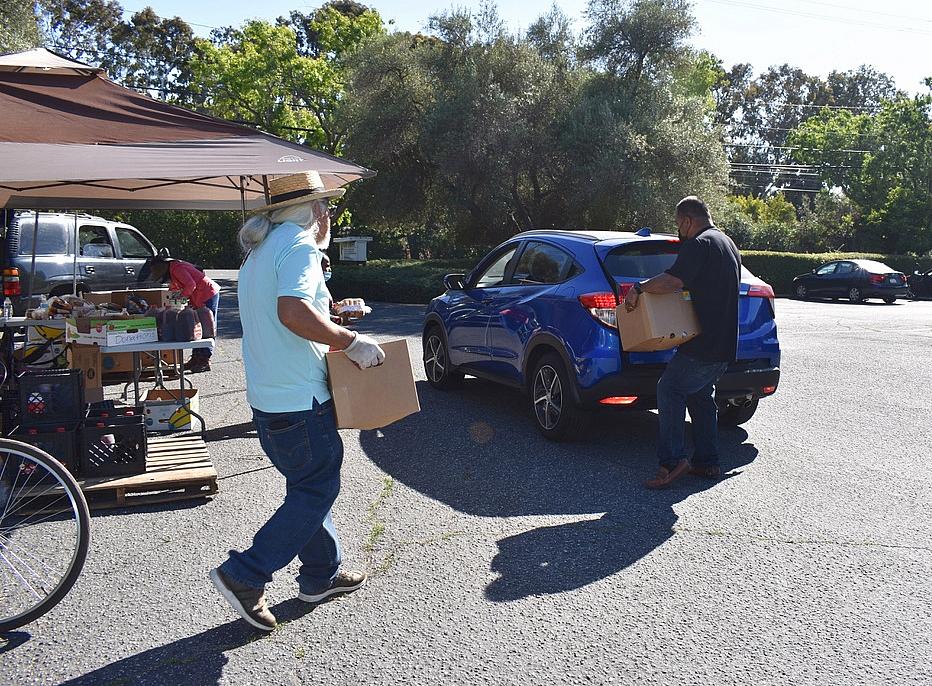 Volunteers help load boxes of food into vehicles after asking drivers how many boxes of food they want on June 4, 2021, at a food distribution site in Palo Alto. Volunteers help load boxes of food into vehicles after asking drivers how many boxes of food they want on June 4, 2021.