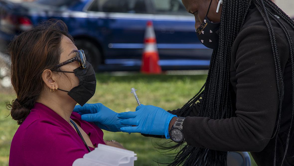 A woman receives a COVID-19 vaccine during a mobile vaccine clinic at the rear of MacArthur Park in Central Long Beach 
