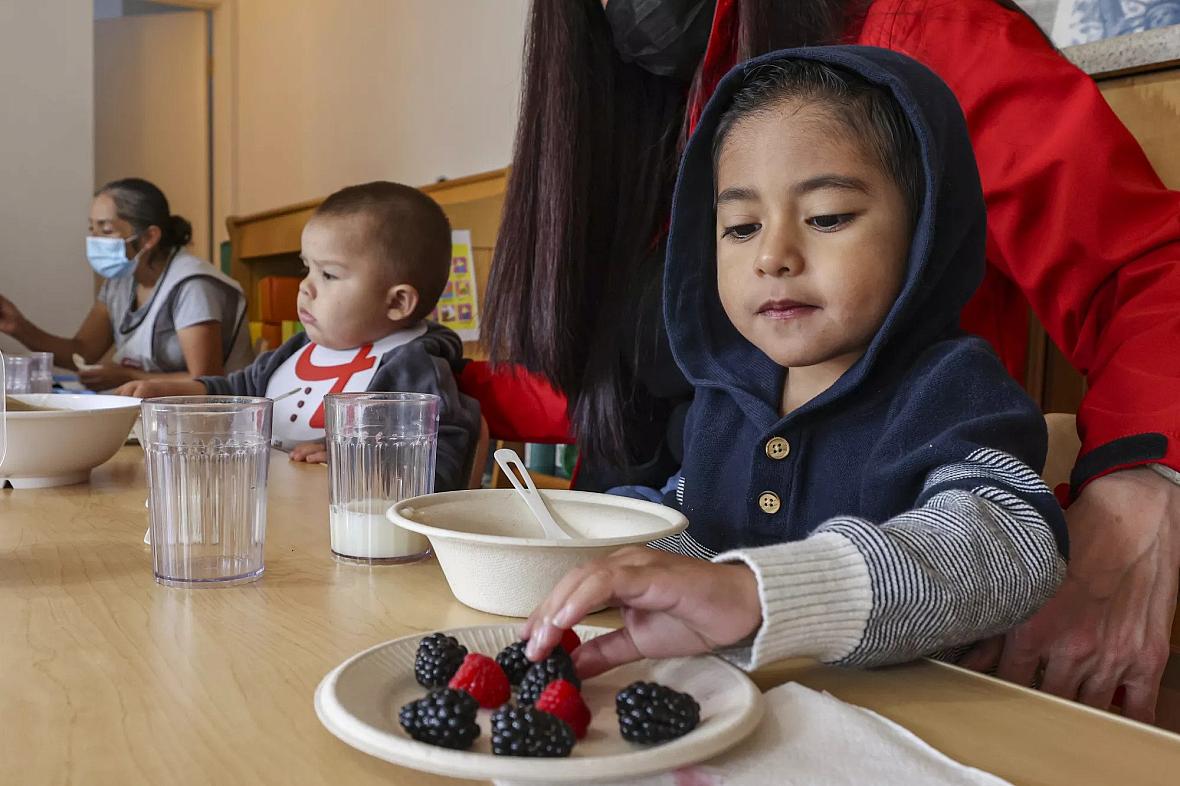 Adriel, 3, eats some berries with the other children whom child care provider Miren Algorri, standing, serves at her home. Adriel, 3, eats some berries with the other children whom child care provider Miren Algorri, standing, serves at her home.