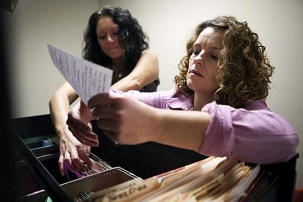 Rachelle Autry, left, and Crystal Copley sort through client files in The Healing Place women's center office. Copley started in detox at The Healing Place in January 2011, and now helps others there