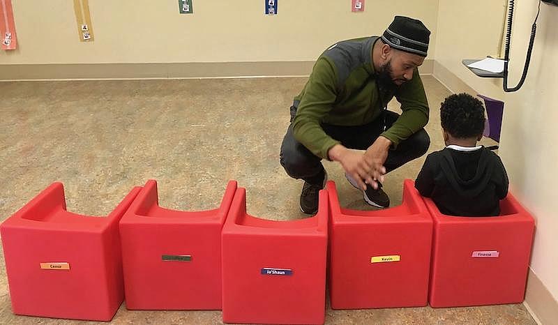 Behavior interventionist Marcus Bundy speaks with three-and-a-half year-old Kevin during the Shoestrings first official cohort.