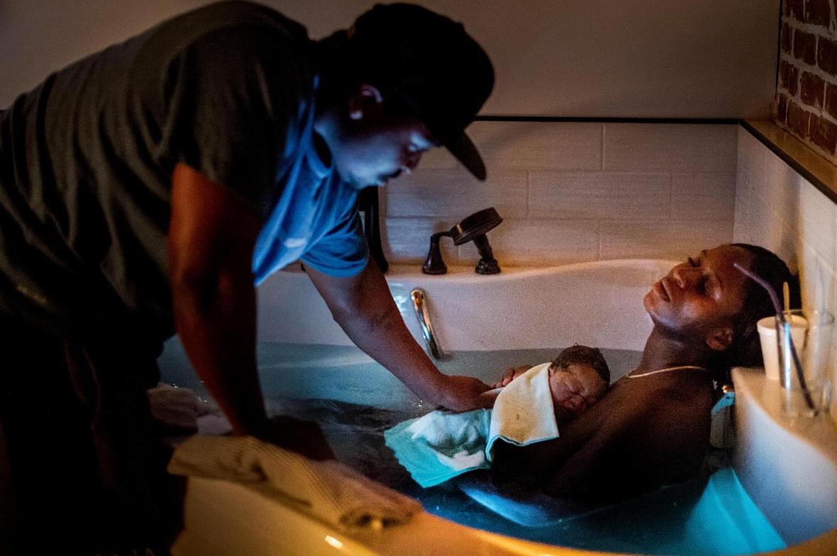 Dennis touches their son as Aysha rests in the birthing bath at Kindred Space LA’s South LA birthing center on Mother’s Day nigh