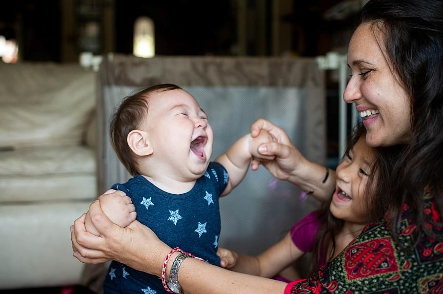 Tameka Issartel and her daughter Nalani, 5, laugh with Tenshin, 7 months, in their El Sereno living room on Thursday, September 9, 2021 where Issartel birthed Tenshin. Midwife Racha Tahani Lawler pulled off her N95 and performed CPR all the way to the hospital after Tenshin struggled to take his first breath. Tameka Issartel and her daughter Nalani, 5, laugh with Tenshin, 7 months, in their El Sereno living room