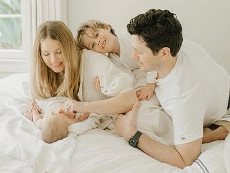 Nicole Taylor sits on the bed where she gave birth to her daughter Lily weeks after being infected with COVID-19 with her husband Sam Rubin and son August by her side. Nicole Taylor sits on the bed where she gave birth to her daughter Lily weeks after being infected with COVID-19