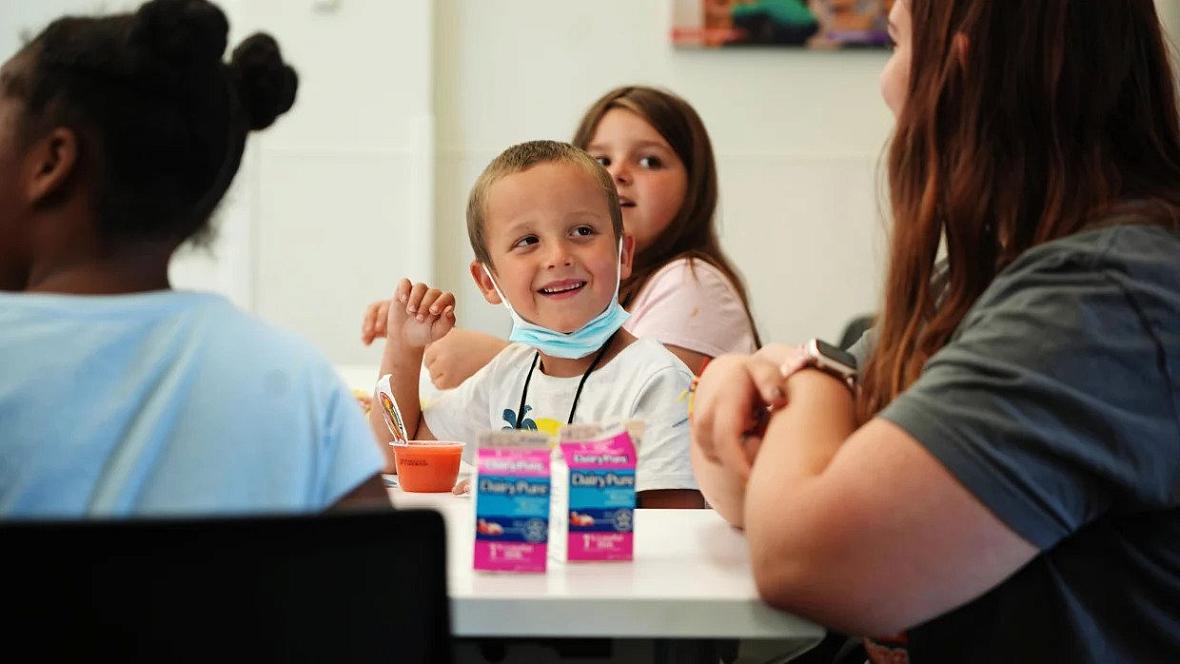 Timmy Schoolcraft, 6, smiles at library volunteer Reta Borton, 15, during the free summer lunch and snack program at the South H
