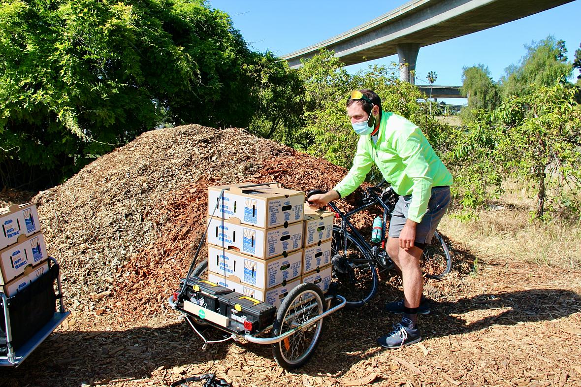 Volunteers with the Silicon Valley Bicycle Coalition load boxes of food onto their bicycles for delivery to households in San Jose on May 1, 2021. The program is a partnership with urban farm Veggielution and other local farms Volunteers with the Silicon Valley Bicycle Coalition load boxes of food onto their bicycles for delivery