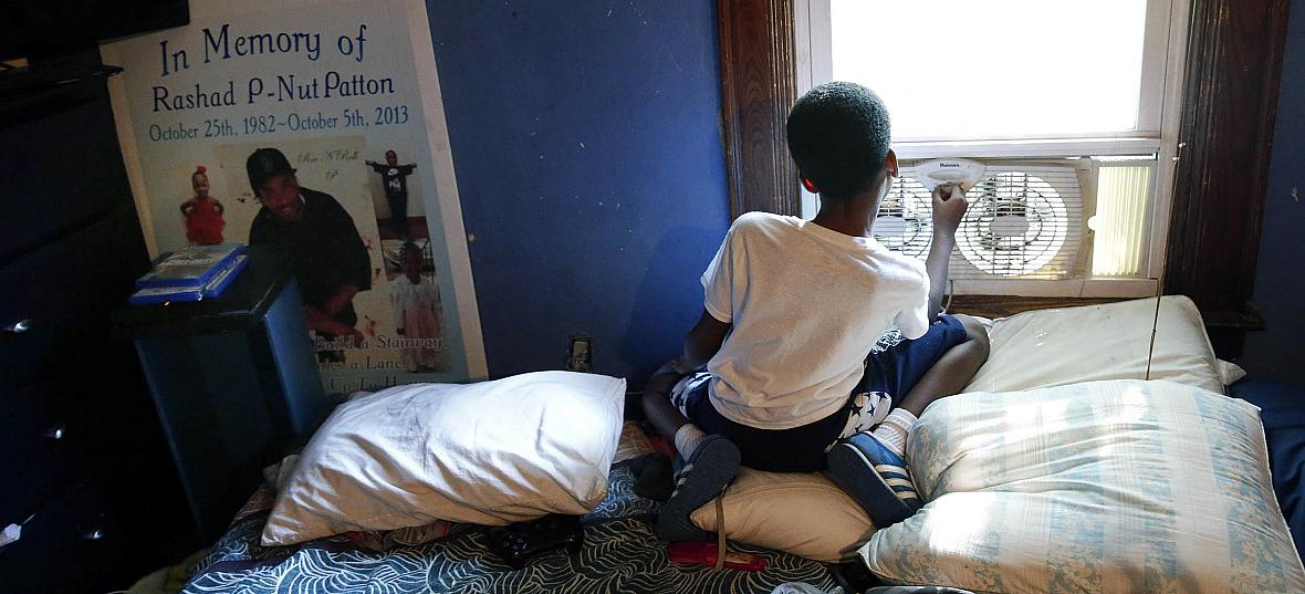 Jayden Lawson, now 9, lost his father to violence in 2013. At Jayden’s left is a poster from his father’s memorial service.