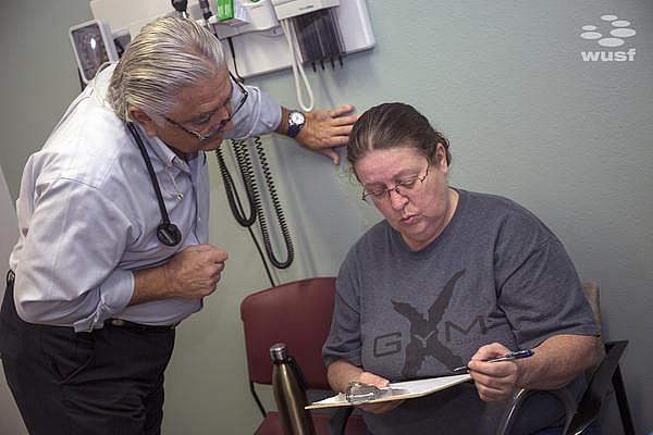 Dr. Ronald Cirillo, left, helps patient Deborah Hatfield fill out paperwork before getting a test to see whether she has hepatitis C. Daylina Miller/ Health News Florida Daylina Miller/ Health News Florida