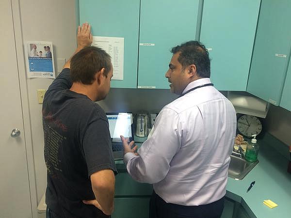 Dr. Ajoy Kumar, right, goes over a patient's blood tests at the St. Petersburg Free Clinic. Julio Ochoa / WUSF Public Media