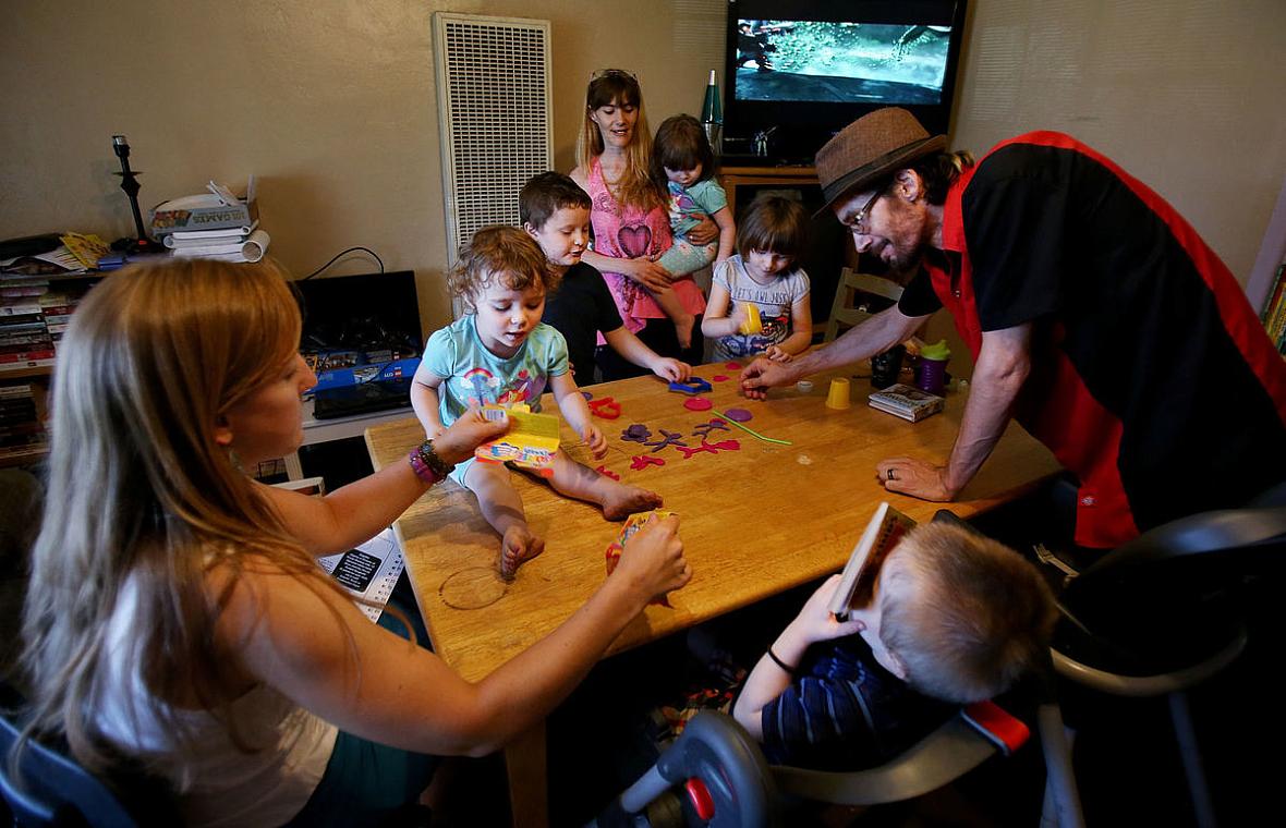 Angela Helseth, left, a family support specialist with Healthy Families, conducts an in-home visit with Nathan Wilson, right, Christine Haley, rear center, and their blended family of six children. Healthy Families has helped Wilson, a first-time dad, learn parenting skills. But because of state funding cuts, only 15 percent of eligible Pima County families can access the program. Mike Christy / Arizona Daily Star 2017