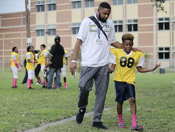 Coach Edgarson Scott walks with Philip Hall as the A.L. Davis Park Panthers 9- and 10-year-old youth football team meets up at the Central City park before heading to a game at Harrell Park on Saturday, October 21, 2017. (Photo by Brett Duke, Nola.com | The Times-Picayune) Photo by Brett Duke, Nola.com | The Times-Picayune