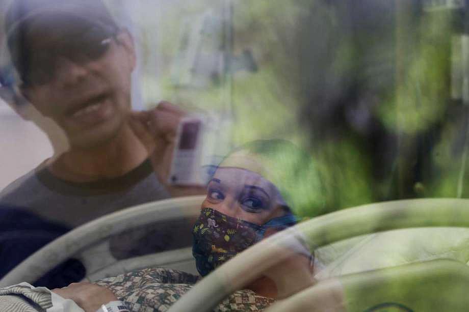 Alex Benavidez, 35, talks with his wife, Kayla, 31, through the window of a maternity room at Uvalde Memorial Hospital