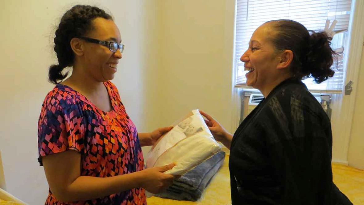 Carmen Perez, of the Children's Hospital of Philadelphia's Community Asthma Prevention Program, gives Victoria Harris mattress covers and a special pillowcase for her children.
