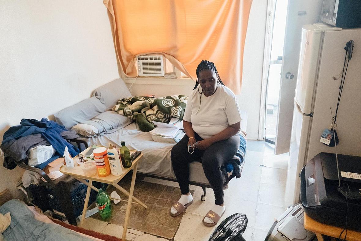 Kim Moore sits on her bed in a small unit of an unpermitted Mid-City apartment complex cited by the city in 2019.
