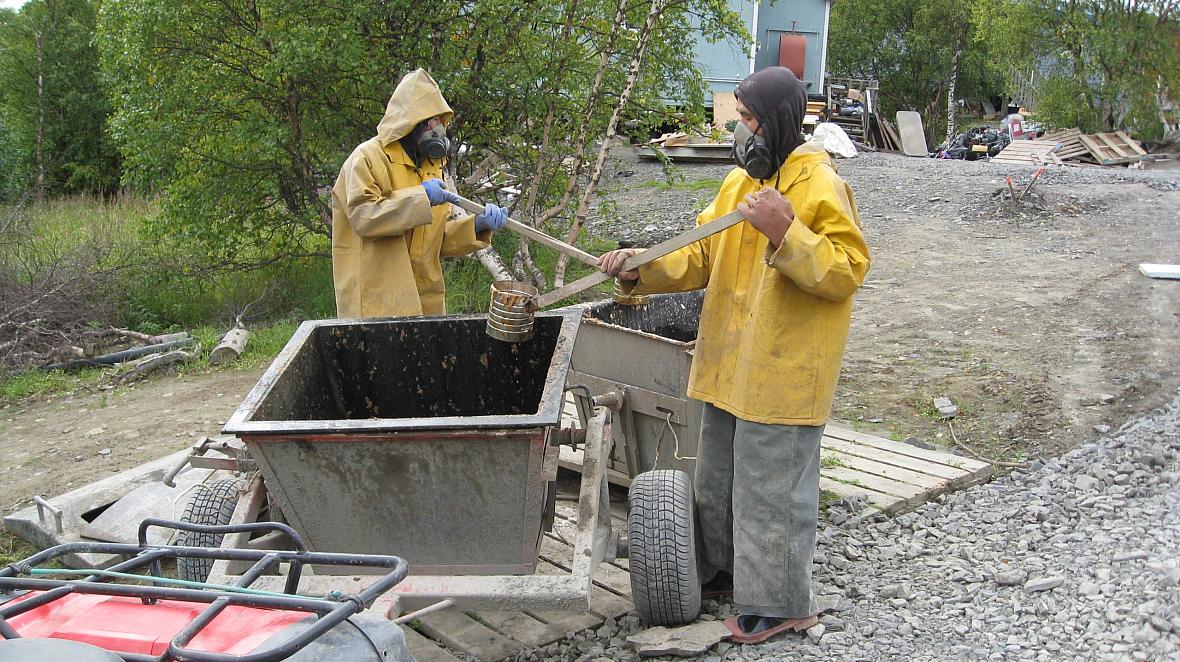 A 2011 photo shows residents of Pitkas Point, Alaska wearing breathing apparatus transfer human waste to a collection bucket