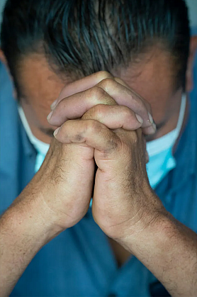 Man folds hands to pray