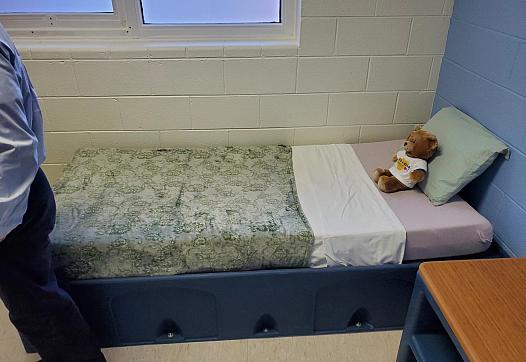 Bed with stuffed bear on it