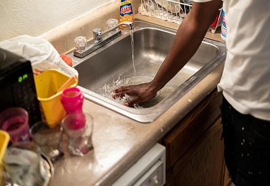 A man washes his hand in the sink.