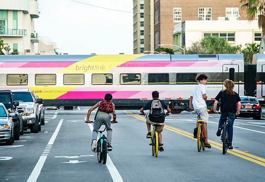 Teens ride bikes down a busy street.