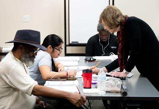 A reading instructor helps a woman decode a series of words during an adult literacy class in Bellaire
