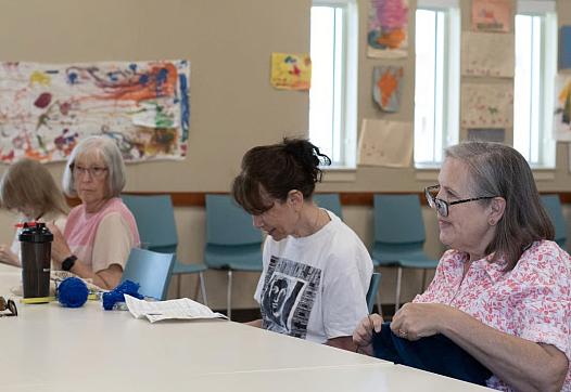 People sitting knitting in a room