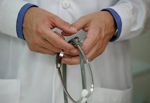 Person wearing white lab coat and holding a stethoscopes