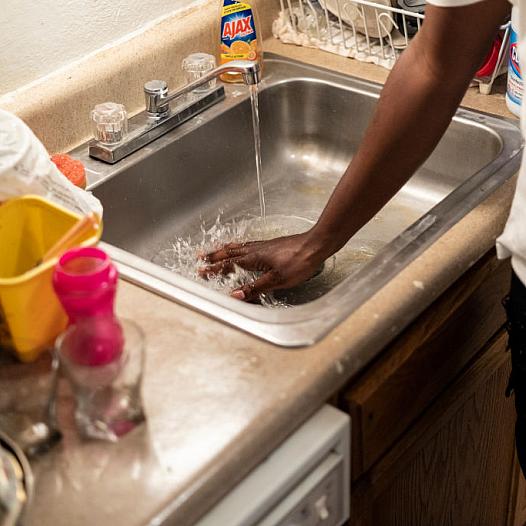 A man washes his hand in the sink.