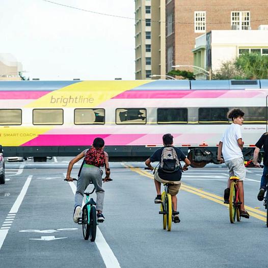 Teens ride bikes down a busy street.