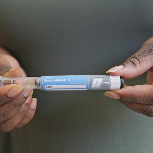 Photo of a Black woman holding GLP-1 medication.
