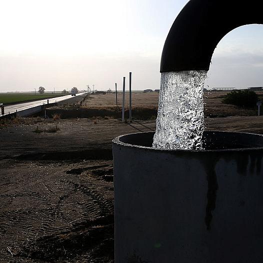 A well pipe pouring water into a large metal tank
