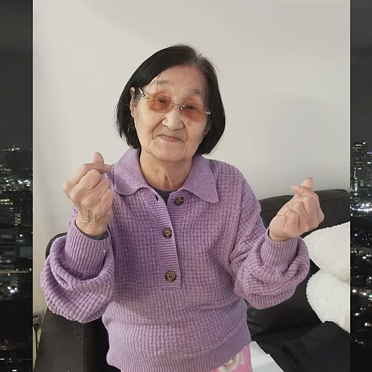 a 97-year-old Korean American woman wears a purple sweater