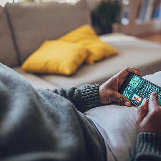 Person holding a mobile phone with a game betting screen on