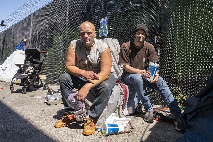 2 people sitting in front of a metal fence