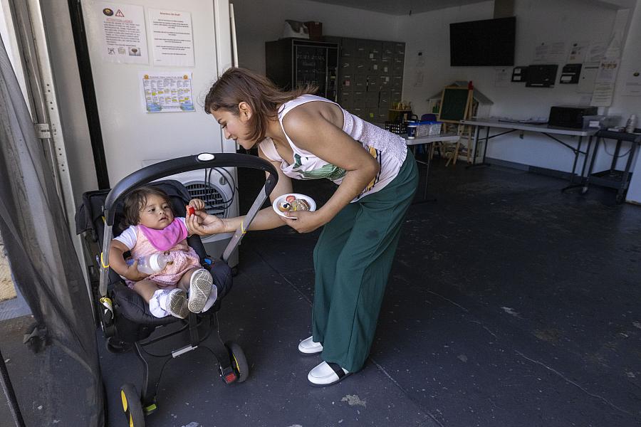 Gladis gives a snack to her daughter at the housing facility where they now live.