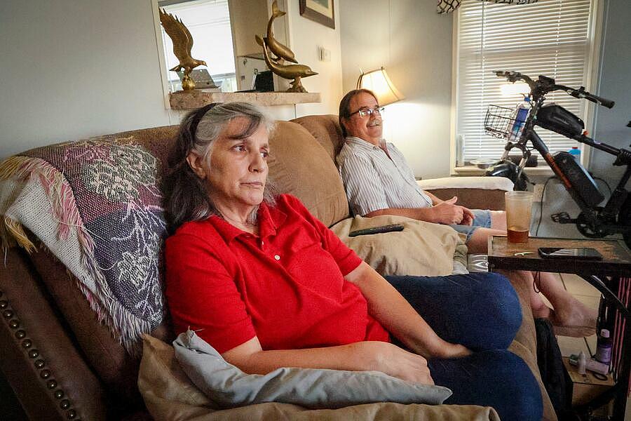 Carmen and Joe Flora IV sit on the couch in their mobile home