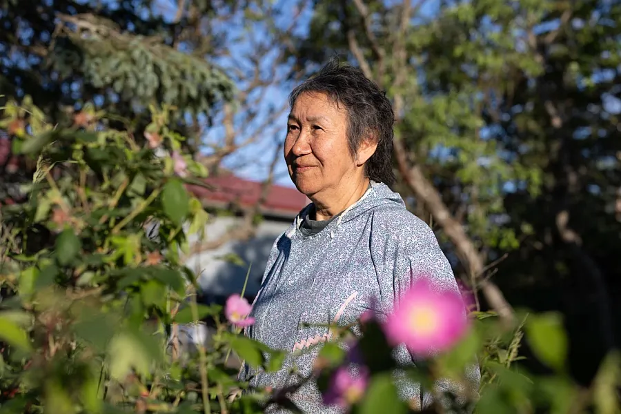 A older women standing outside her home 