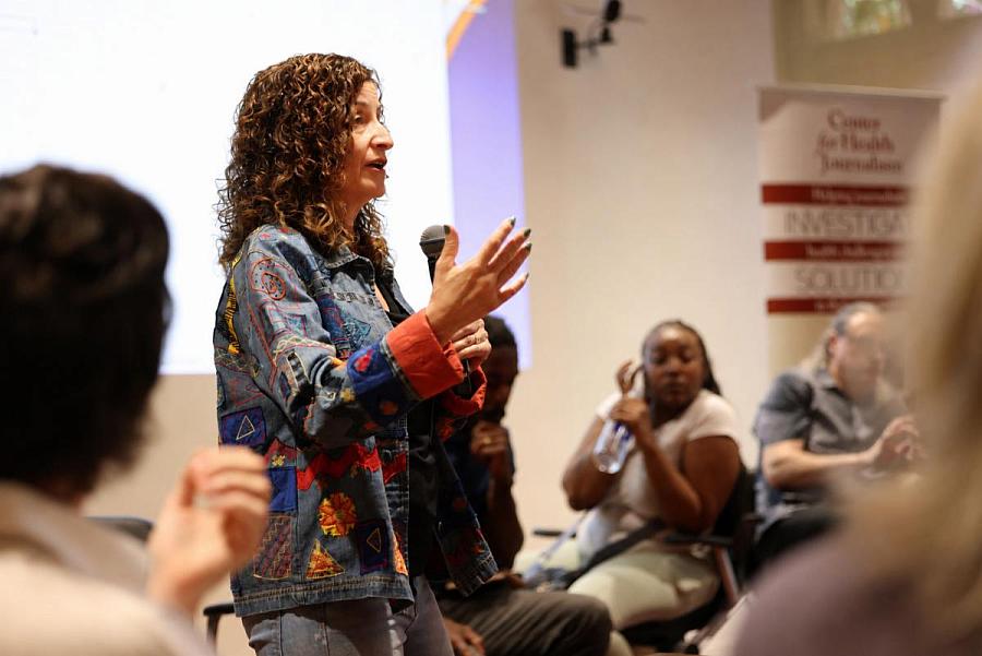 Speaker addresses attendees during a Center for Health Journalism event while holding a microphone.