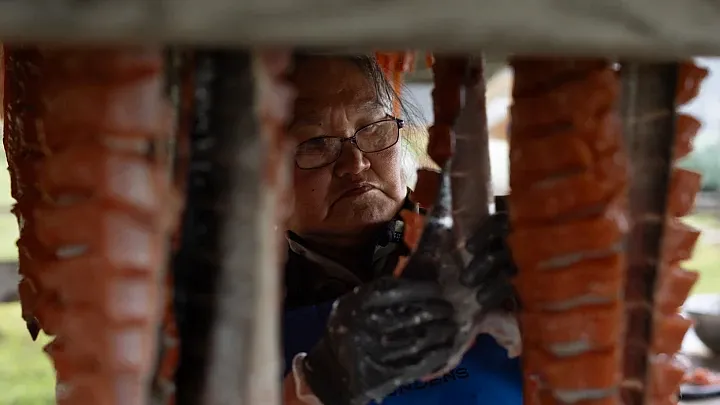 Helen Friend cuts and hangs salmon outside her home