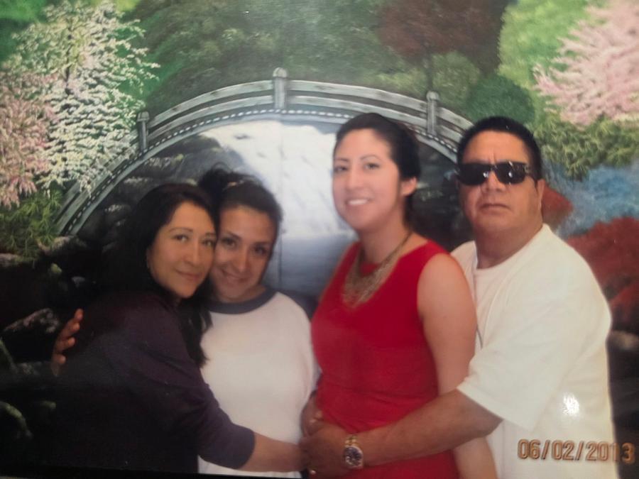 A Latino family of four pose for a picture in front of a painted bridge at Central California Women’s Facility in Chowchilla, California