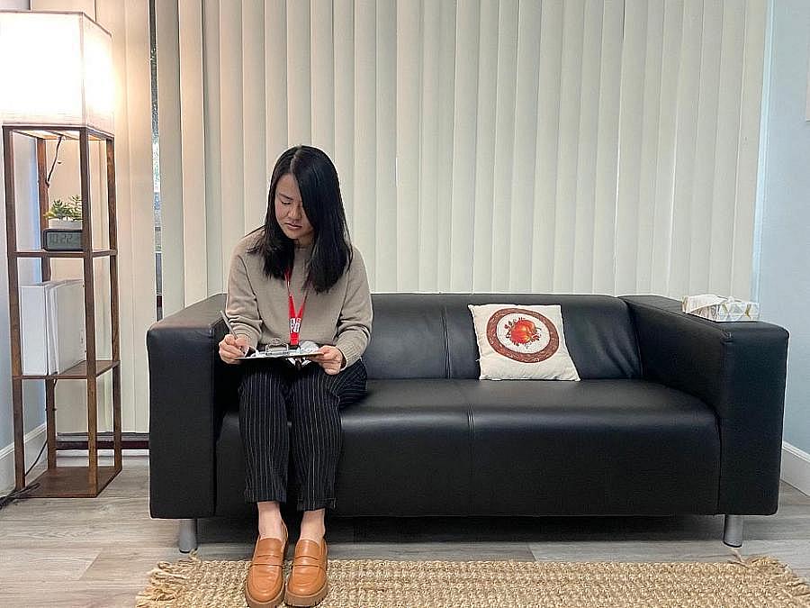 Person seated on couch holding clipboard