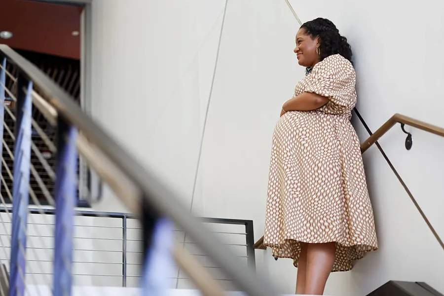 A pregnant women standing by the stair 