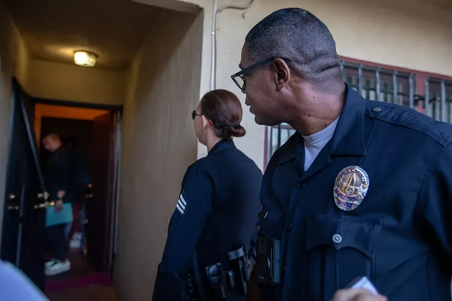 Couple of LA Police officers with a mental health officer outside a house