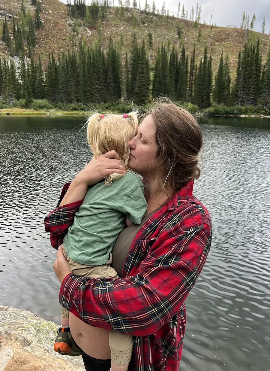 Image of a pregnant woman holding her child beside a lake