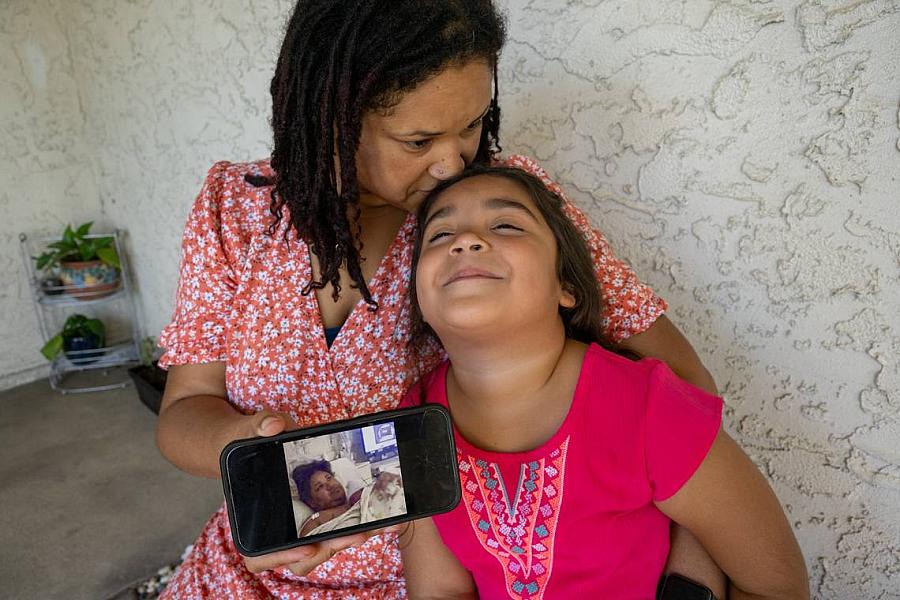 A mom shows a photo on her phone to her daughter