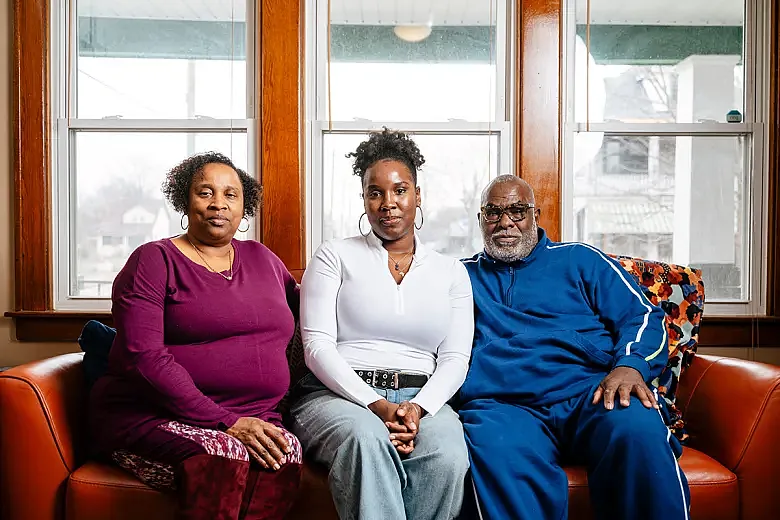 Priscilla, Bethany, and Vanzell Howard pose for a photo on their couch in the home.