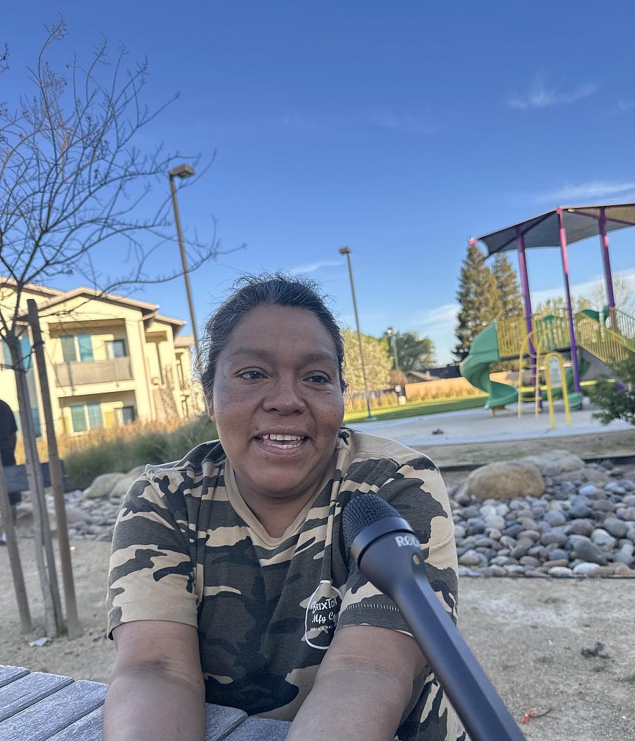 Adela Leon, in a camo t-shirt, speaks into a microphone